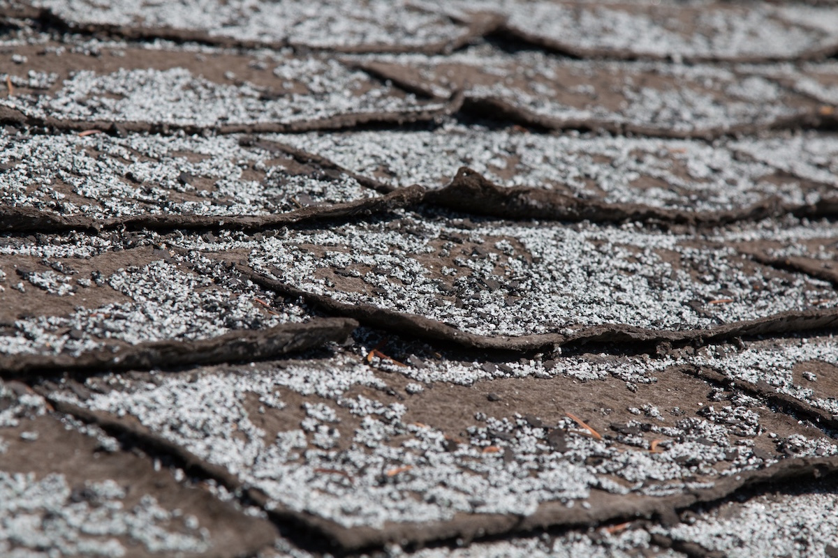 Old worn out asphalt shingles on the roof of a residential home.