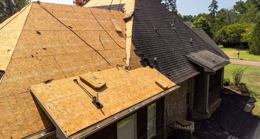 House with new roof being installed over sheathing after hail damage