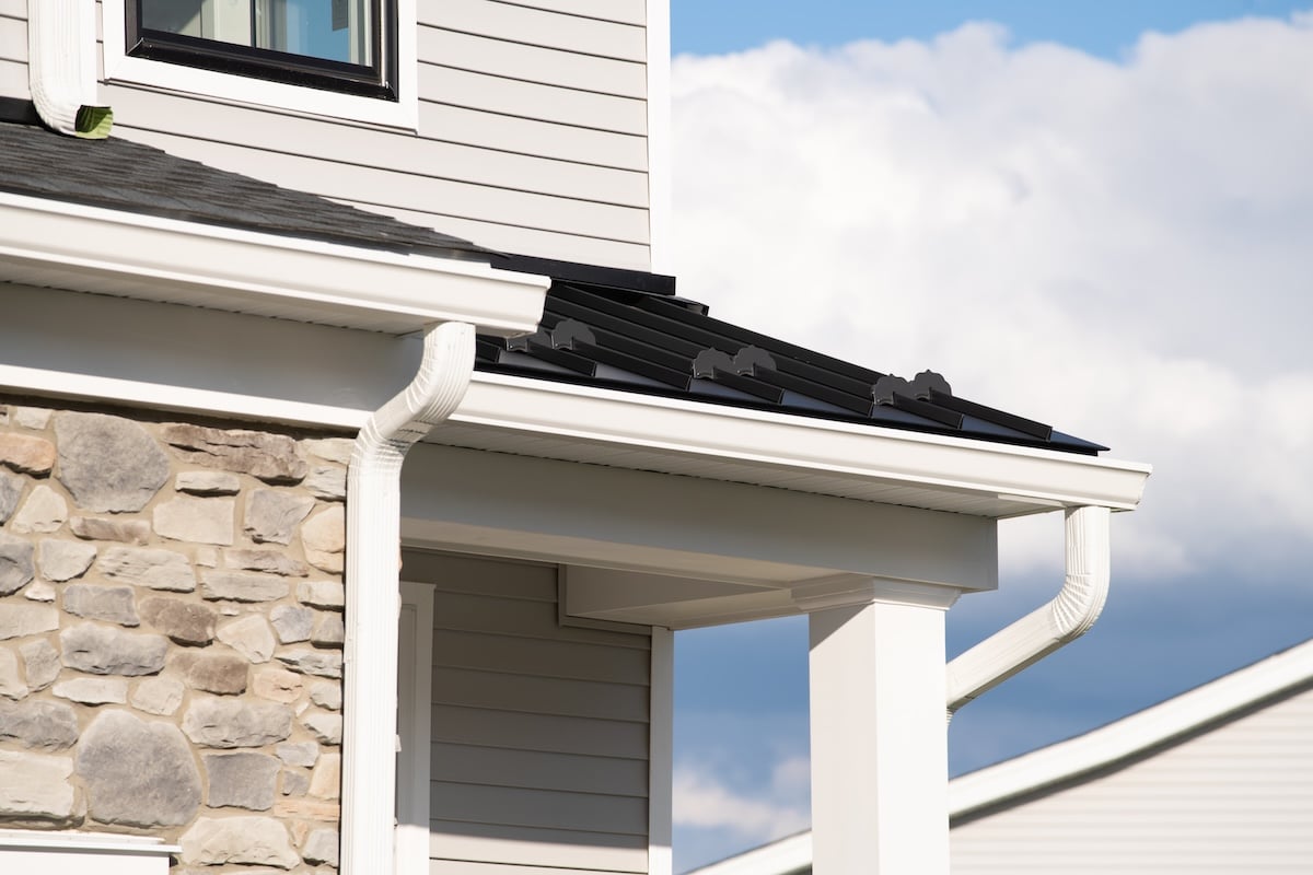 New rain gutter on a white home against blue sky drain corner outside