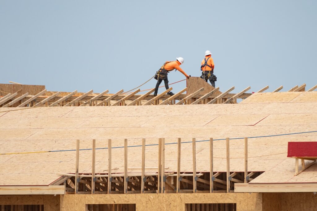 Preparing the roof deck for OSB installation. Cutting OSB sheets for roof. roofing. Roof deck for installation. Roof frame for beam installation. Male roofer carpenter working on roofs structure.