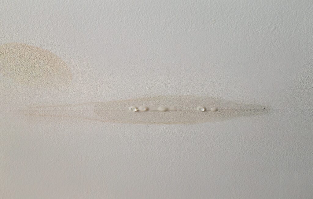 Water is leaking from drywall ceiling in home room, water damage. Water dripping from crack.