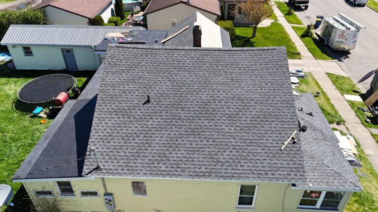 A pale yellow house with a grey shingle roof