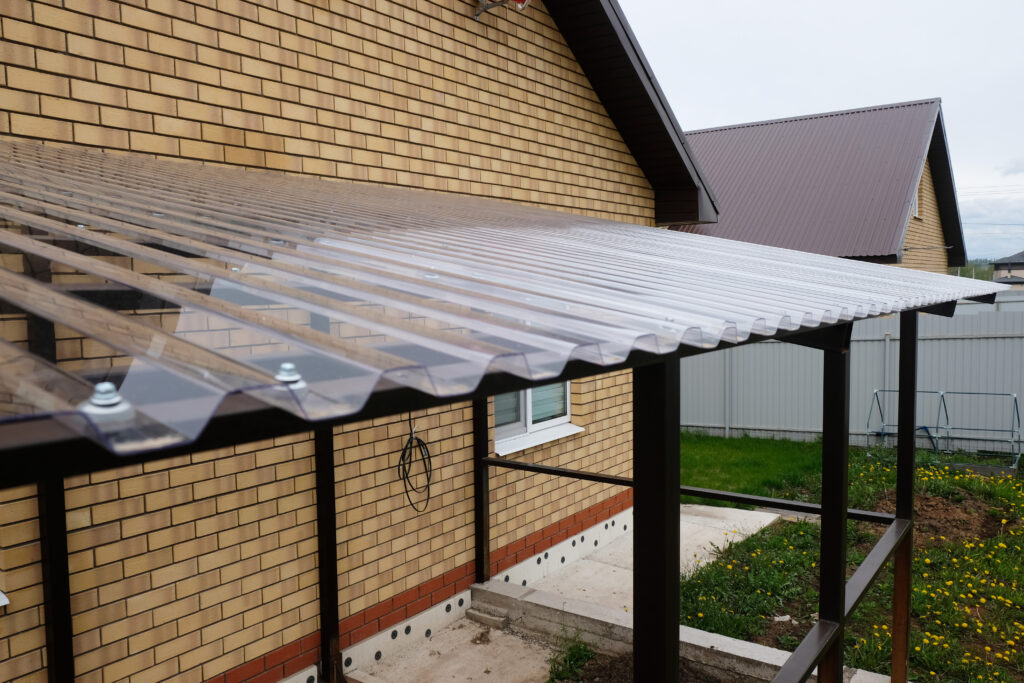 corrugated plastic roof panels Canopy of a country house terrace made of metal structures and transparent roof made of profiled polycarbonate, construction process