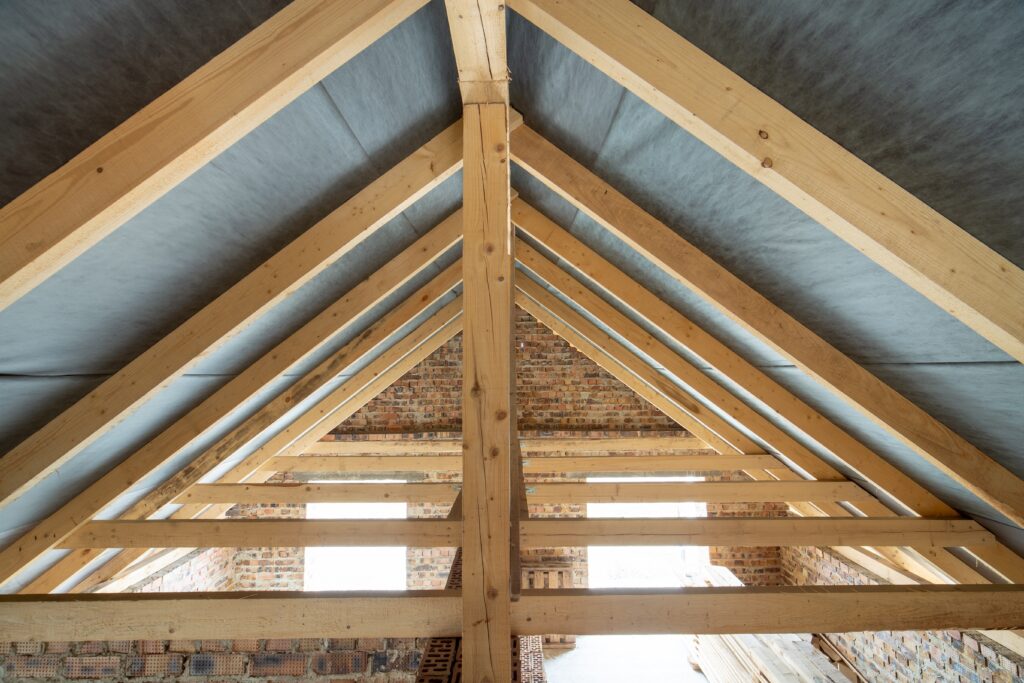 roof rafters vs trusses Attic space of a building under construction with wooden beams of a roof structure and brick walls. Real estate development concept.