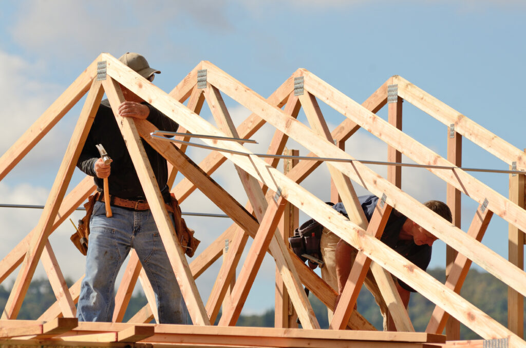 roof rafters vs trusses workers building roof Layout and installation of roof rafters on a new commercial residential construciton project by framing contactors