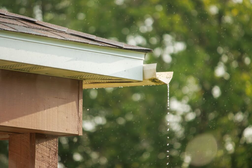 seamless gutters vs traditional pouring rain trees on the back