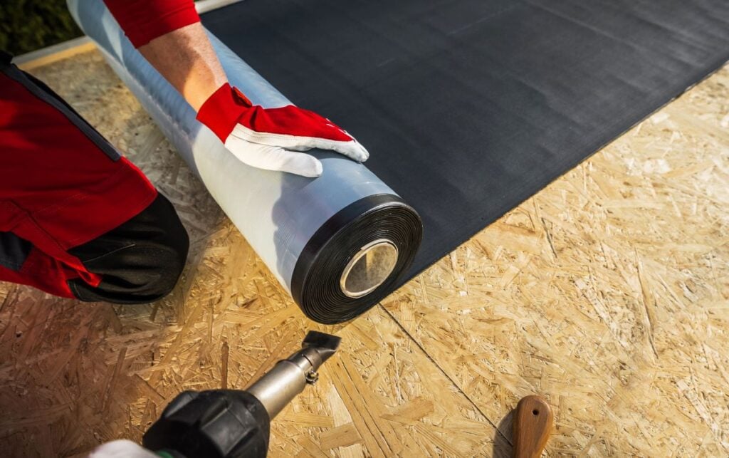 guy unrolling EPDM roof roll roofing material